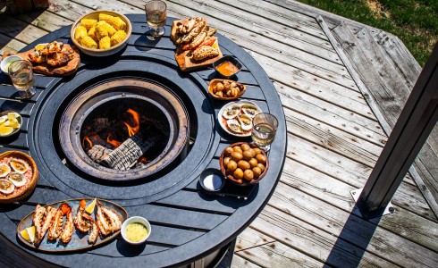 Recipe Blog - Seafood Platter - Top down of flame table with fire in center and seafood on wooden plates surrounding